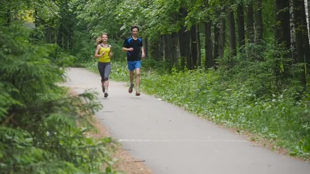 Lyckliga par joggar i parken, slow motion — Stockvideo