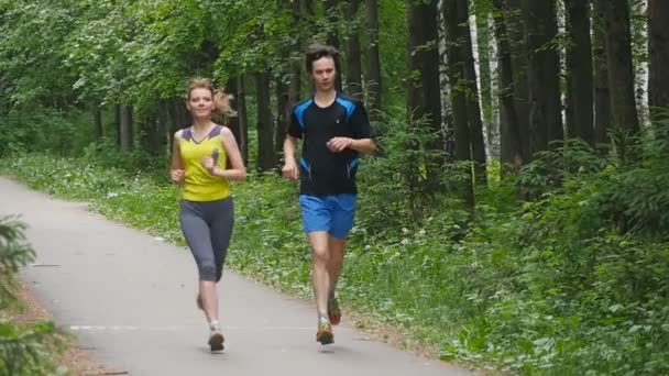 Gelukkige paar joggen in het park, slow-motion — Stockvideo