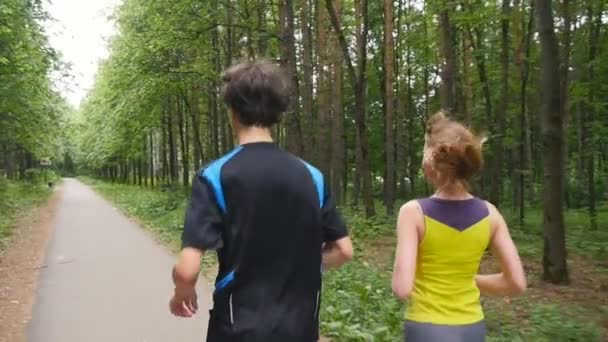 Счастливая пара бегает в парке, замедленная съемка — стоковое видео