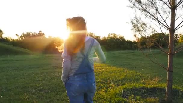 Una mujer embarazada corre sobre la hierba al atardecer — Vídeo de stock