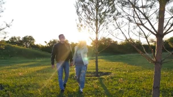 Amantes andando em um campo ao pôr do sol — Vídeo de Stock