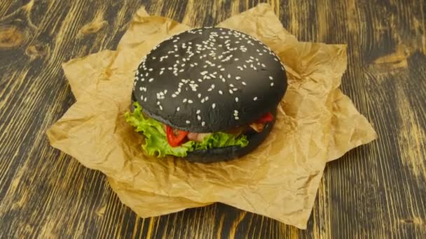 Ahşap masa üzerinde siyah burger — Stok video