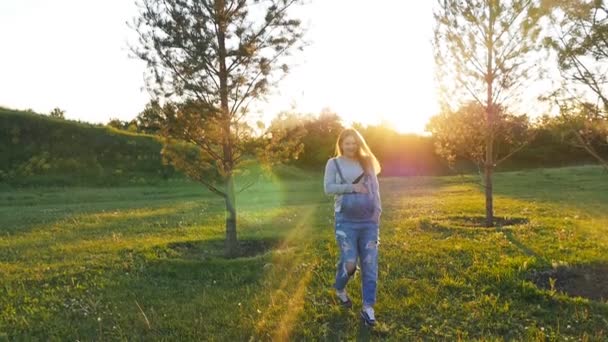 Hamile bir kadın günbatımında çimenlerin üzerinde çalışıyor — Stok video