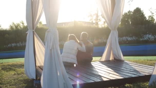 Back view of young happy couple sitting at sunset — Stock Video