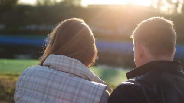 Vista posteriore della giovane coppia felice seduta al tramonto — Video Stock