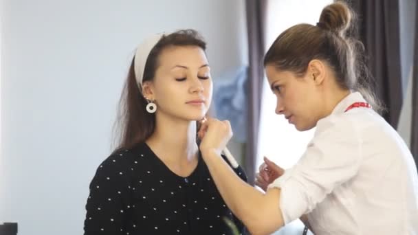 Визажист делает макияж для молодой девушки — стоковое видео