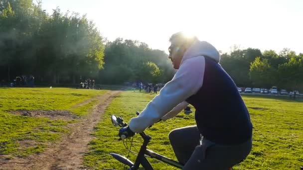 Młodzi i rowerzysta w parku — Wideo stockowe