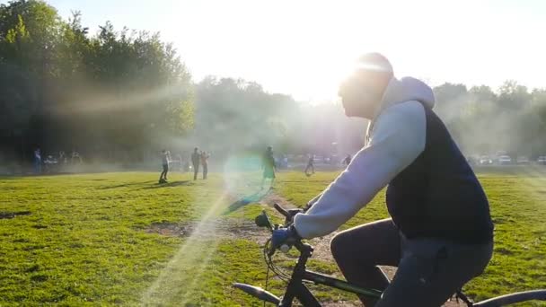 Νέοι και ποδηλάτης στο πάρκο — Αρχείο Βίντεο