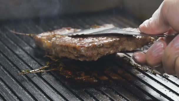 Een kok opduikt een biefstuk van vlees op een grill in slow motion — Stockvideo