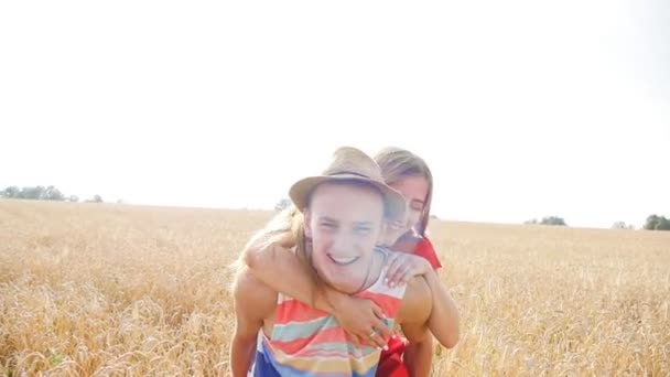 Young, happy couple have a piggy back in the field — Stock Video