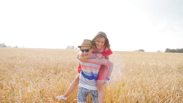 Young, happy couple have a piggy back in the field — Stock Video