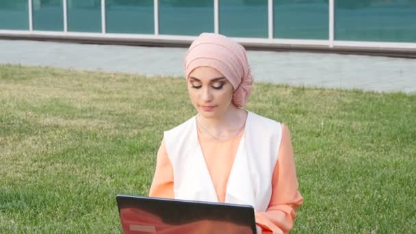 Hermosa chica musulmana en el parque con portátil — Vídeo de stock
