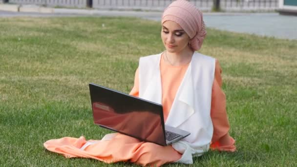 Menina muçulmana bonita no parque com notebook — Vídeo de Stock