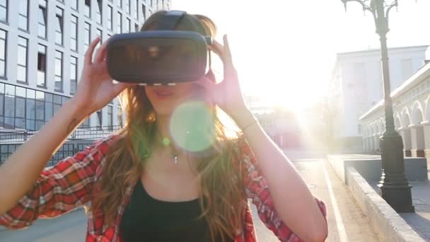 Chica con un dispositivo de realidad virtual en la ciudad — Vídeos de Stock