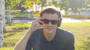 Genç adam, yeşil çim kulaklıklarla