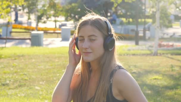 Joven hermosa mujer disfrutando de la música al aire libre en los auriculares — Vídeos de Stock