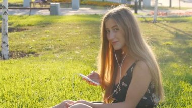 Telefon ile çimenlerin üzerinde genç kadın