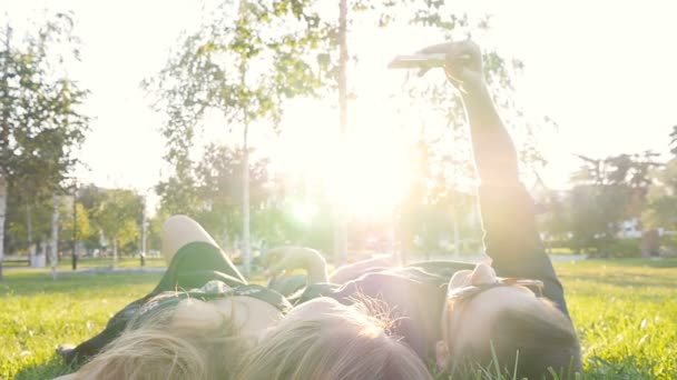 Gelukkig jonge verliefde paar maken selfie met slimme telefoon liggend op het gras — Stockvideo