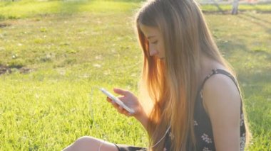 Telefon ile çimenlerin üzerinde genç kadın