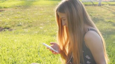 Telefon ile çimenlerin üzerinde genç kadın