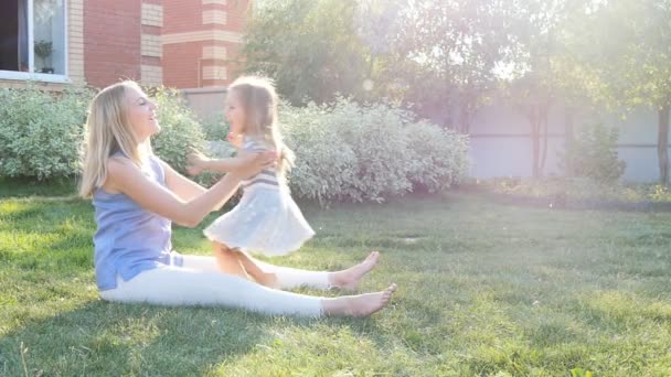 Young mum embraces a daughter on the lawn — Stock Video