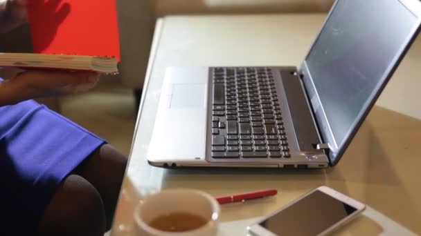 Beautiful young woman is seating indoors at a cafe restaurant, holding a coffee cup while using her laptop pc — Stock Video