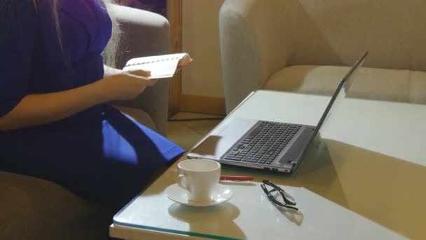 Belle jeune femme est assis à l'intérieur dans un café restaurant, tenant une tasse de café tout en utilisant son ordinateur portable pc — Video