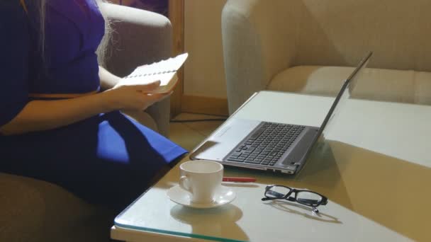 Mooie jonge vrouw is binnenshuis zitplaatsen in een café-restaurant, een koffiekopje te houden tijdens het gebruik van haar laptop-pc — Stockvideo