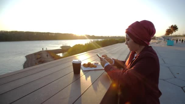 Jovem mulher muçulmana vestindo hijab tendo coffee break ao ar livre no fundo da cidade — Vídeo de Stock