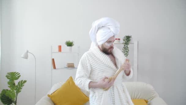 Молодой привлекательный мужчина весело танцует с полотенцем на голове после процедур ванны — стоковое видео