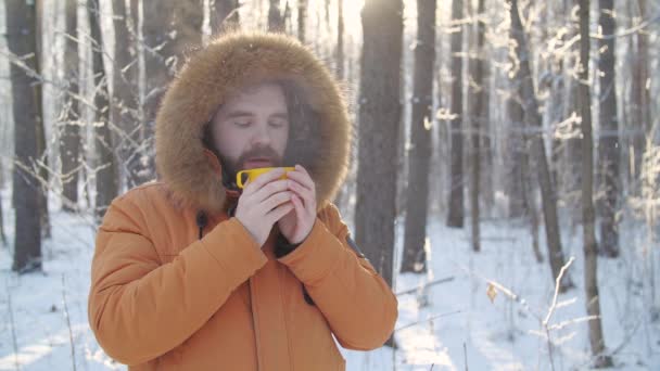 Turismo de invierno y concepto de senderismo. Barba hombre con bebida caliente en el bosque de invierno — Vídeo de stock