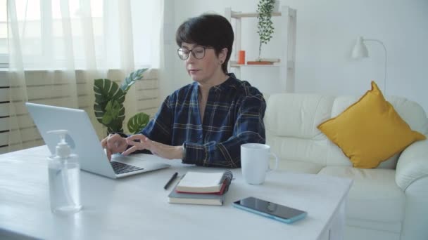Conceito de trabalho remoto. Mulher madura de pijama trabalhando em casa com computador notebook — Vídeo de Stock