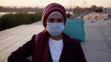 Başörtüsü takan Müslüman kadın dışarıda kameraya bakıyor.