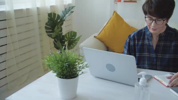 Conceito de trabalho remoto. Mulher madura de pijama trabalhando em casa com computador notebook — Vídeo de Stock