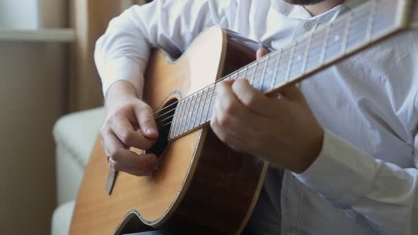 kytarista hraje na akustickou kytaru doma