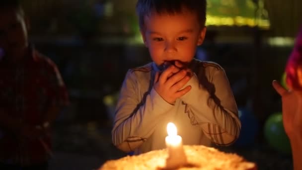 El retrato de cerca de un niño apaga las velas del pastel. — Vídeo de stock