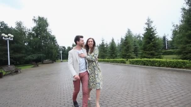 Όμορφο ζευγάρι περπατά κάτω από ομπρέλα στο πάρκο αργή — Αρχείο Βίντεο