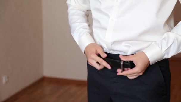 De jonge man corrigeert een riem op broek. — Stockvideo