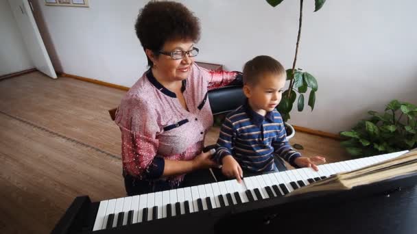 Мальчик учится играть на фортепиано — стоковое видео