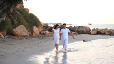Kumsalda yürüyen bir çift. Genç ve mutlu ırklar arası bir çift sahilde yürüyor.