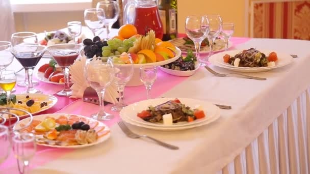 Geserveerd voor een bankettafel. Wijnglazen met servetten, glazen en salades. — Stockvideo