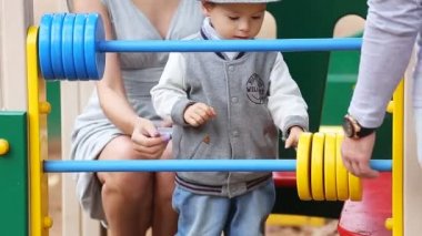 Baba Anne ve oyun parkında oynayan çocuk