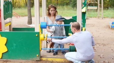 Baba Anne ve oyun parkında oynayan çocuk