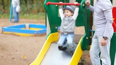 Baba Anne ve oyun parkında oynayan çocuk