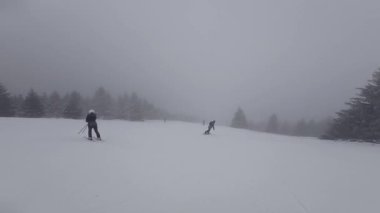 Bir kayakçı kötü hava ve görüş mesafesinde karlı bir yamaçtan aşağı kayar. Birinci şahıs görünümü.