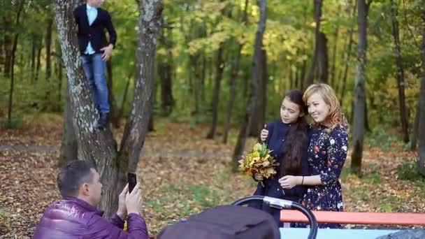 Escena otoñal de la joven familia feliz tomando selfies con su smartphone en el parque — Vídeos de Stock