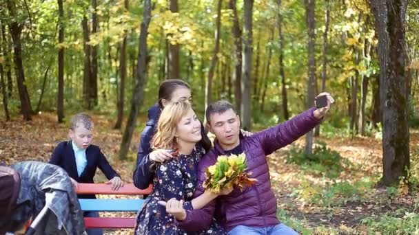 Höstens scen av glada unga familjen som selfies med sin smartphone i parken — Stockvideo