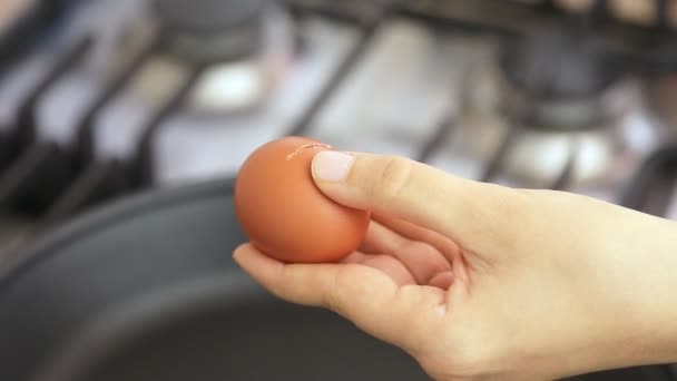 Vrouw die eieren in fry pan barsten — Stockvideo