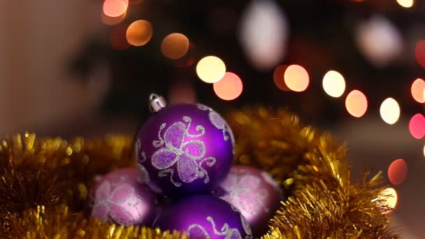 Tři fialové vánoční koule na světlém pozadí bokeh