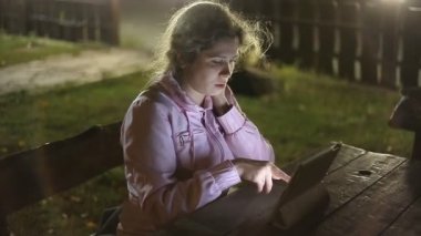 Kız parkta bir bankta oturmuş elektronik tablet ile